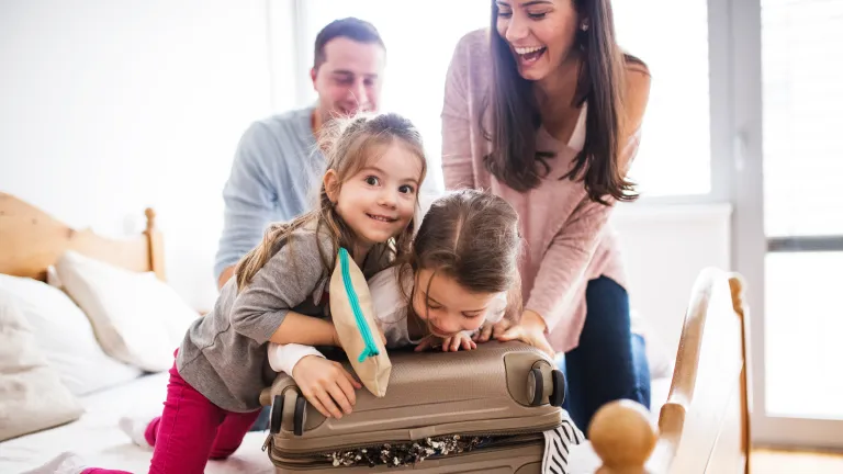 familia (madre, padre, hijo e hija) haciendo una valija arriba de una cama