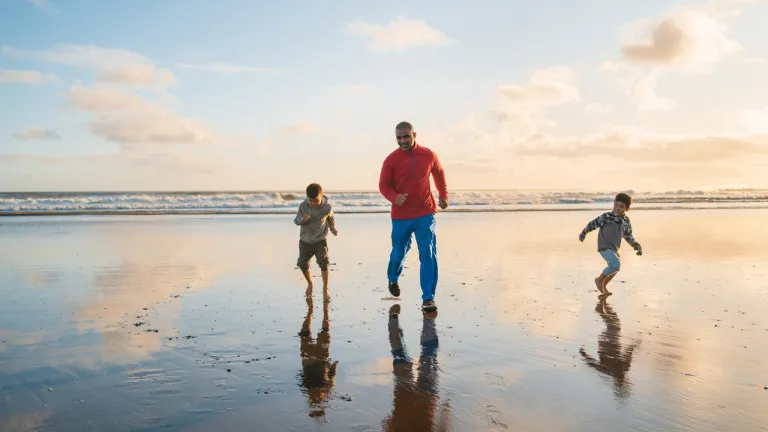 padre e hijos corriendo en la playa
