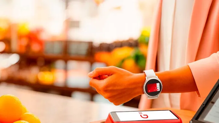 Persona pagando en un pos con su reloj de muñeca garmin con una tarjeta Santander