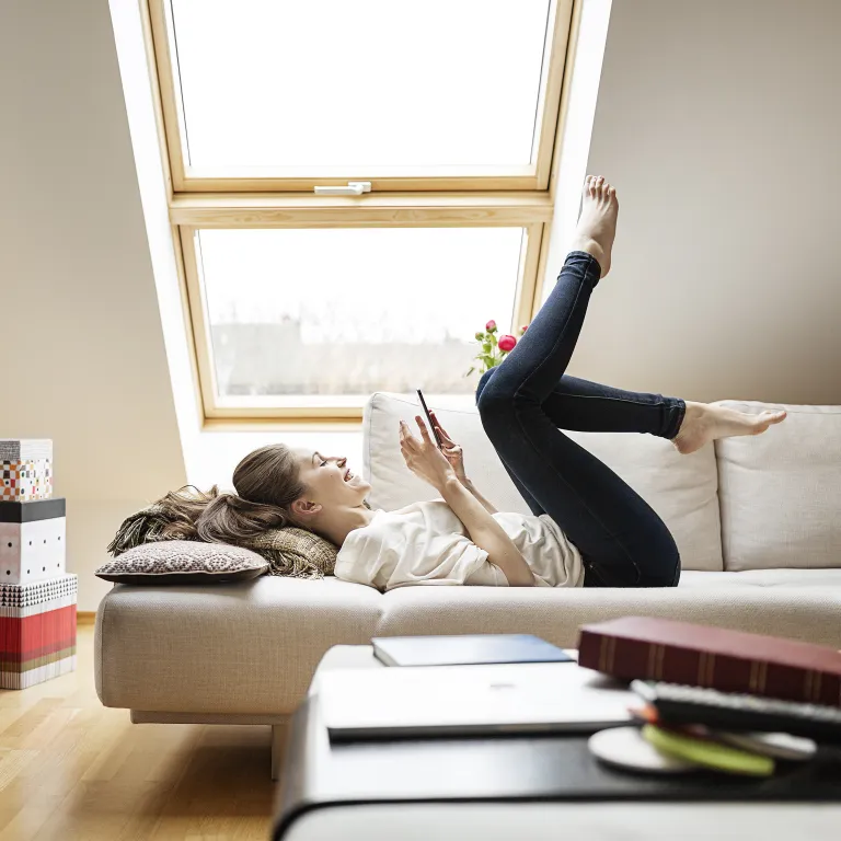 mujer con celular en un sillón mirando el celular