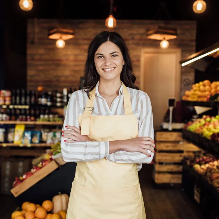 mujer sonriendo con verduleria detrás
