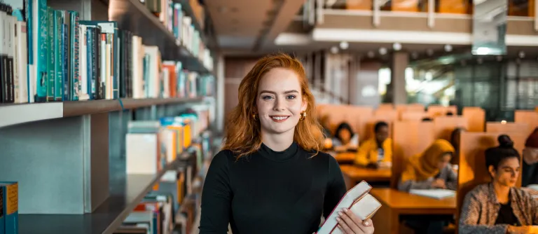 mujer joven en bibloteca con libros