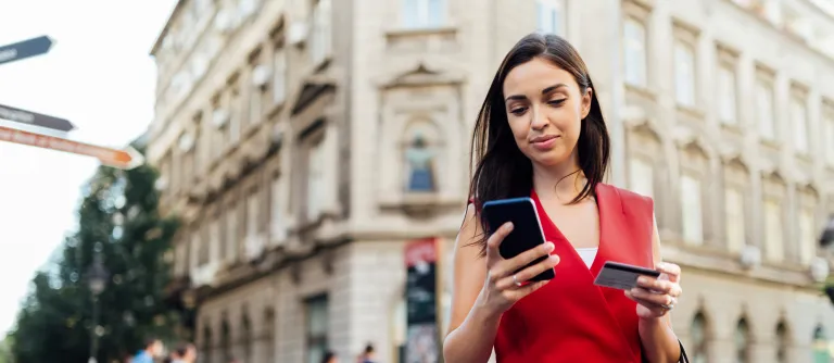 mujer con celular y tarjeta en la mano