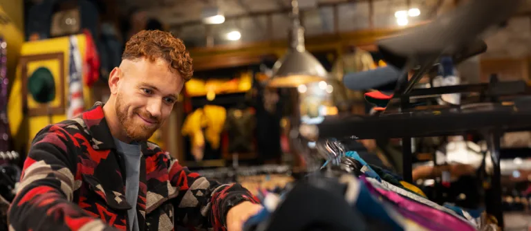 hombre mirando ropa para comprar en una tienda