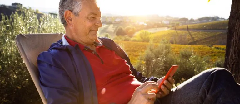 hombre sentado afuera con telefono