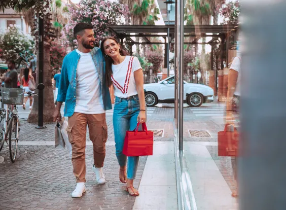 una pareja jovén caminando por la calle y mirando una vidriera